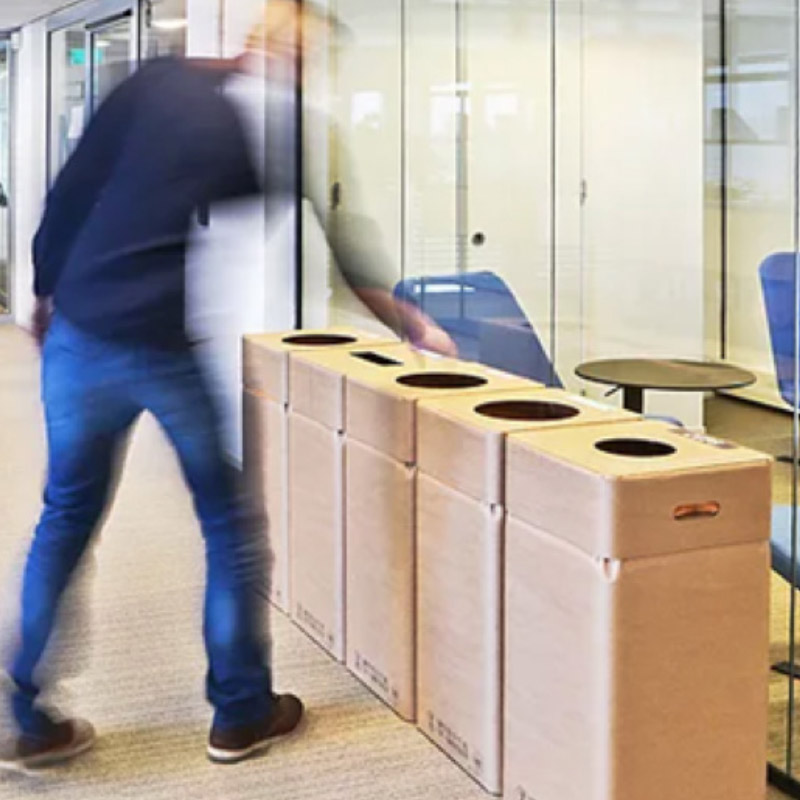 een persoon gooit afval weg bij een afvalsorteereiland
