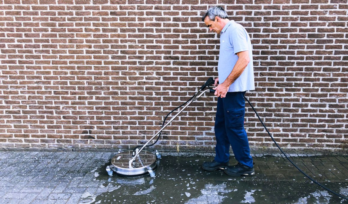 Man maakt de straatstenen schoon met behulp van een professionele hogedrukreiniger