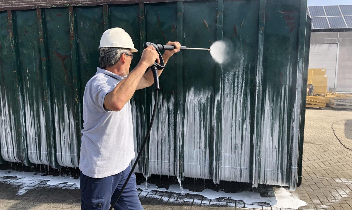 Man maakt een container schoon met een hogedrukreiniger