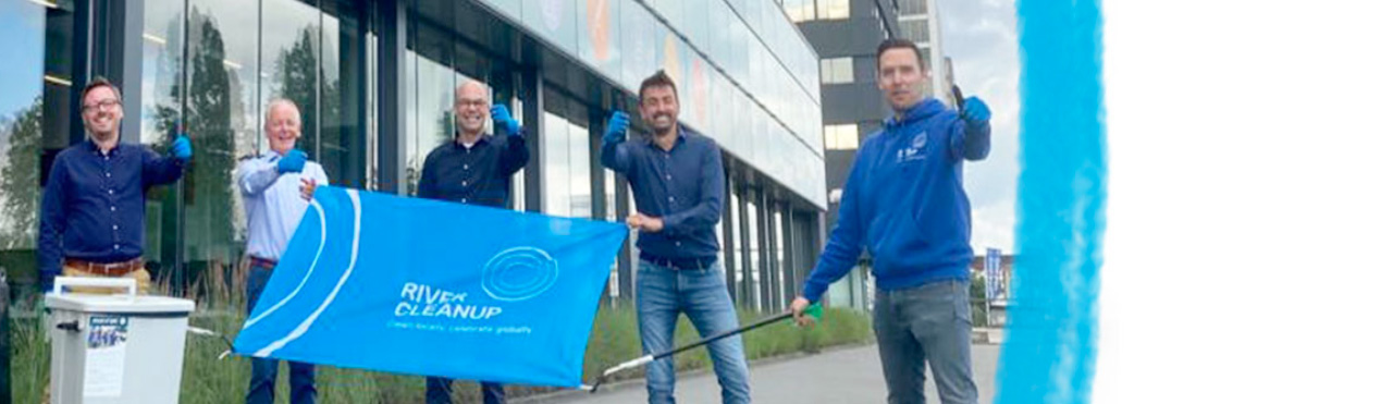 4 mannelijke leden van het BOMA MT houden een vlag vast met he tlogo van River Clean up